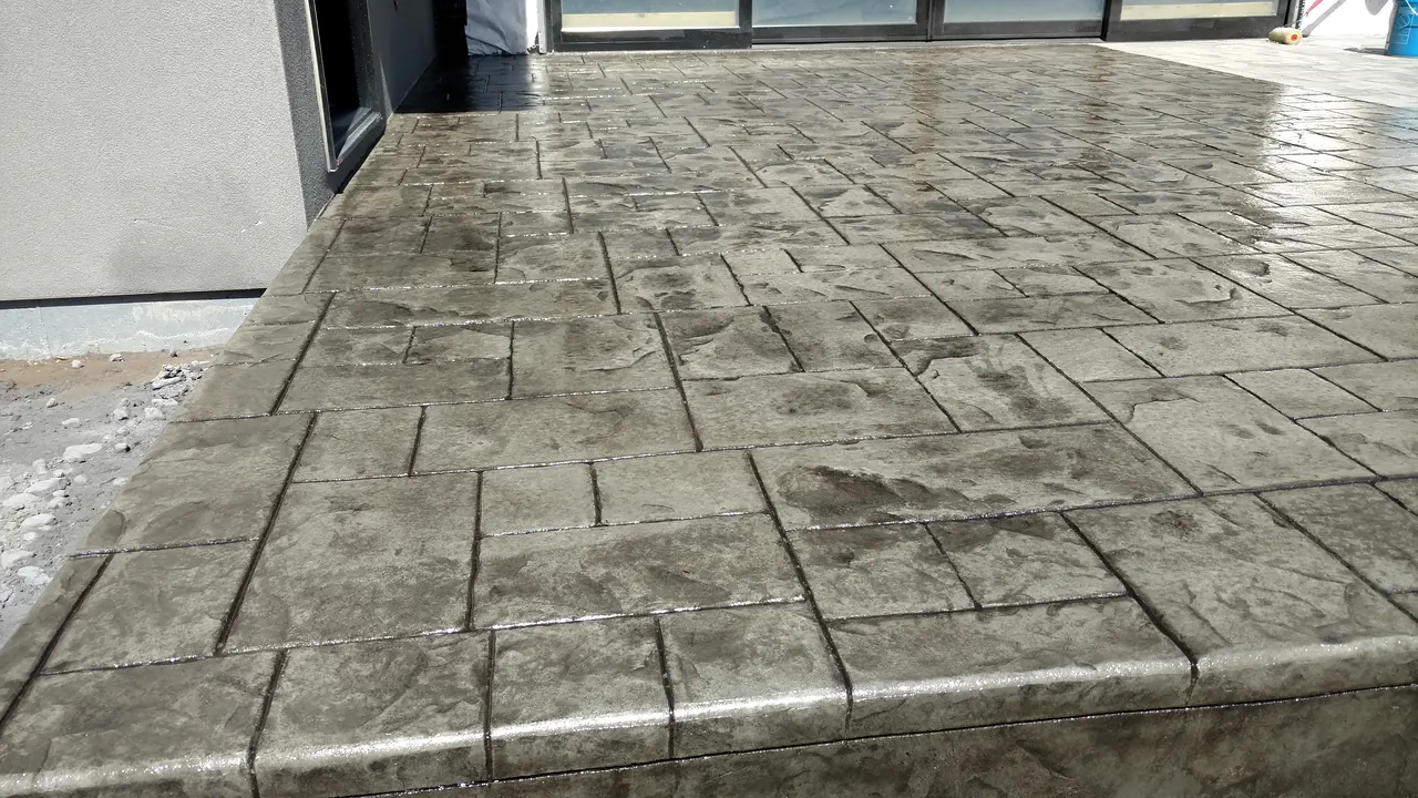 Freshly sealed ashlar-slate stamped patio with a tooled bullnose edge