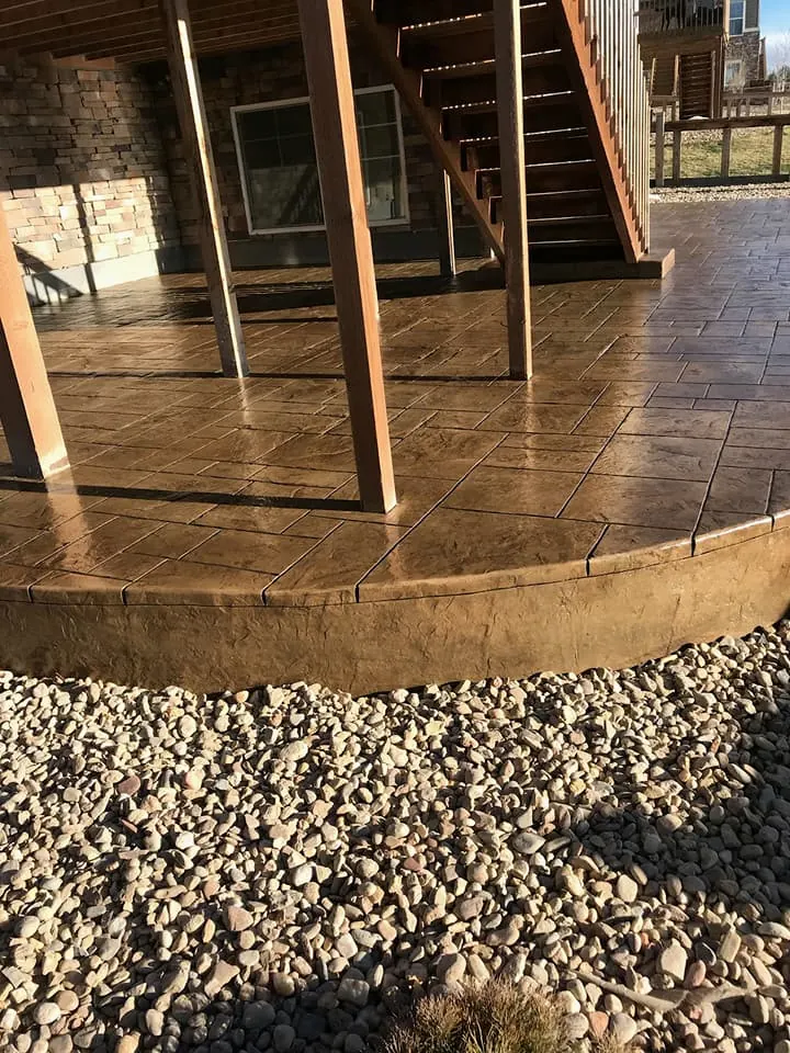 Curved stamped patio tucked under a deck