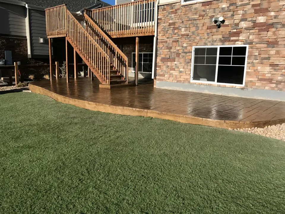 Stamped patio wrapping around a raised deck and stairs